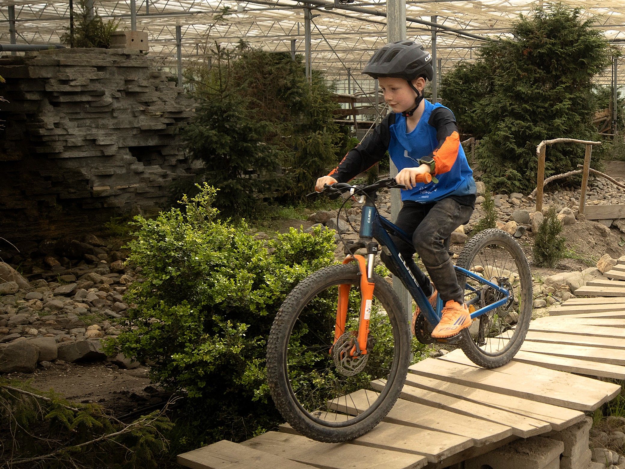 Kind op een mountainbike rijdt over een houten brug op het indoor parcours in Almere