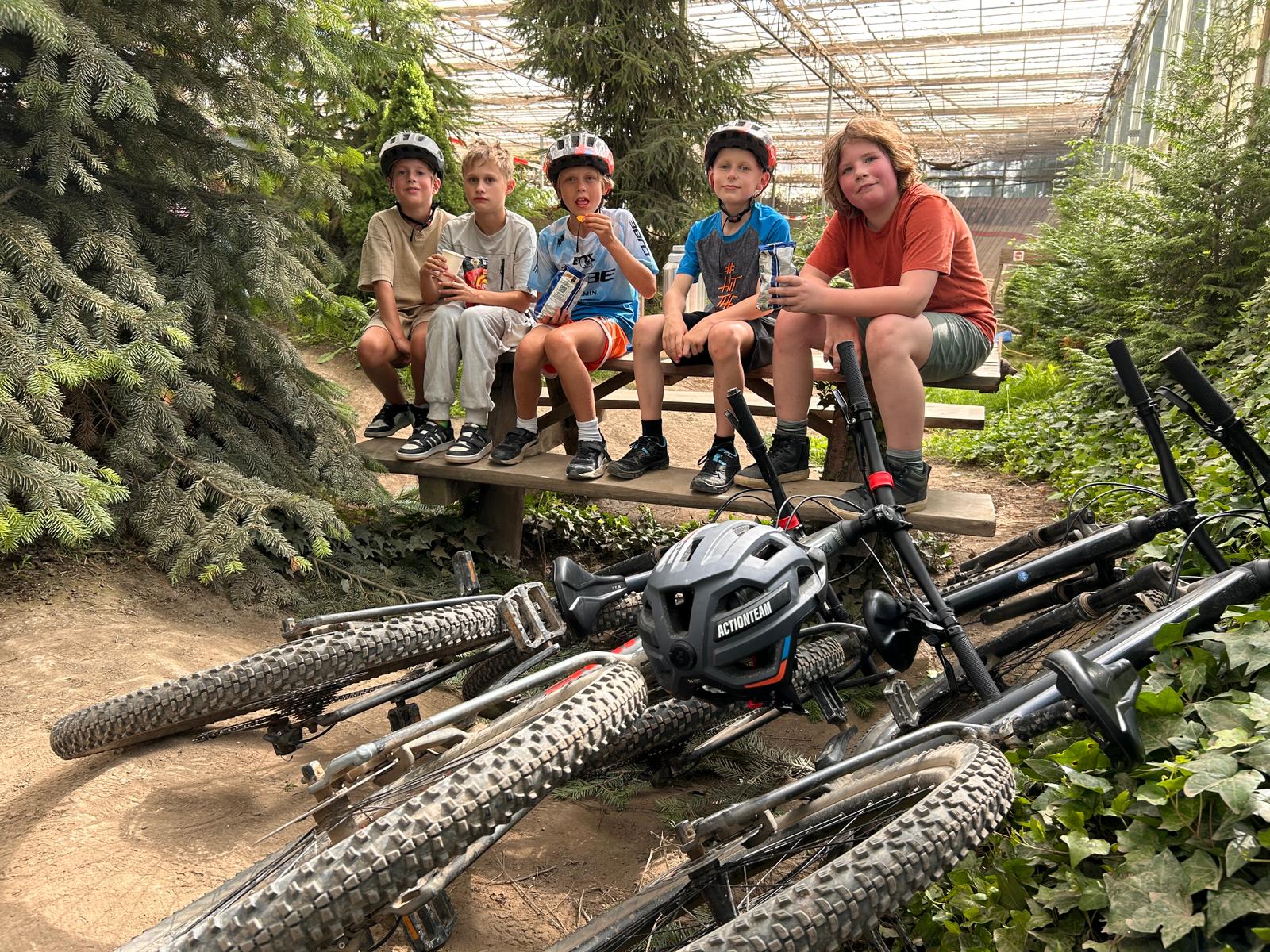Vijf kinderen zitten op een picknicktafel op het parcours in Almere met hun mountainbikes ervoor